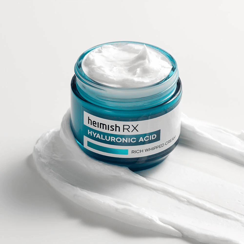 Heimish RX Hyaluronic Acid Rich Whipped Cream in un barattolo di vetro blu con consistenza ricca e soffice, distribuito su uno sfondo bianco. Crema viso intensamente idratante con acido ialuronico per un'idratazione profonda e pelle morbida.