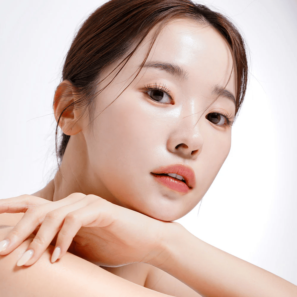 Primo piano di una donna con pelle radiosa e idratata. La sua bellezza naturale è esaltata da un'illuminazione morbida, che dona un aspetto fresco e sano.