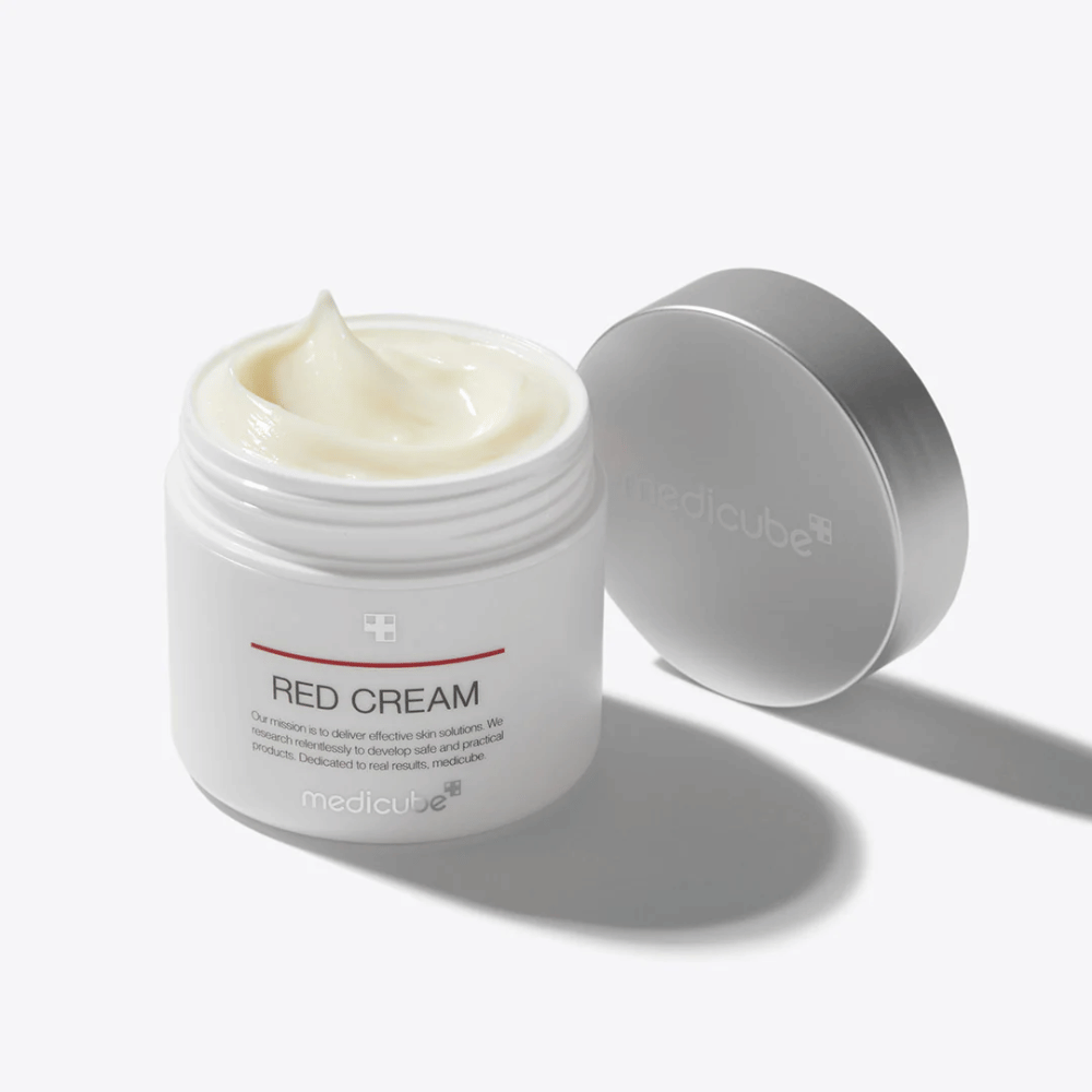 Barattolo aperto con medicube Red Cream 50ml – una crema viso giallo chiaro in confezione bianca con coperchio argentato, sviluppata per la pelle soggetta ad acne.