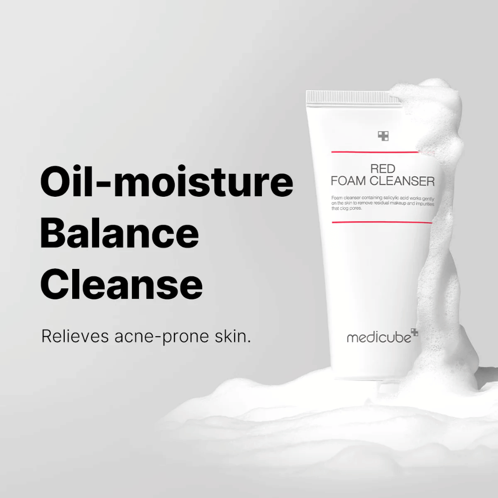 Tubo con Medicube Red Foam Cleanser in piedi tra schiuma spumeggiante. Il testo "Oil-moisture Balance Cleanse" appare a sinistra, con la descrizione "Allevia la pelle incline all'acne" sotto. Lo sfondo è grigio chiaro.