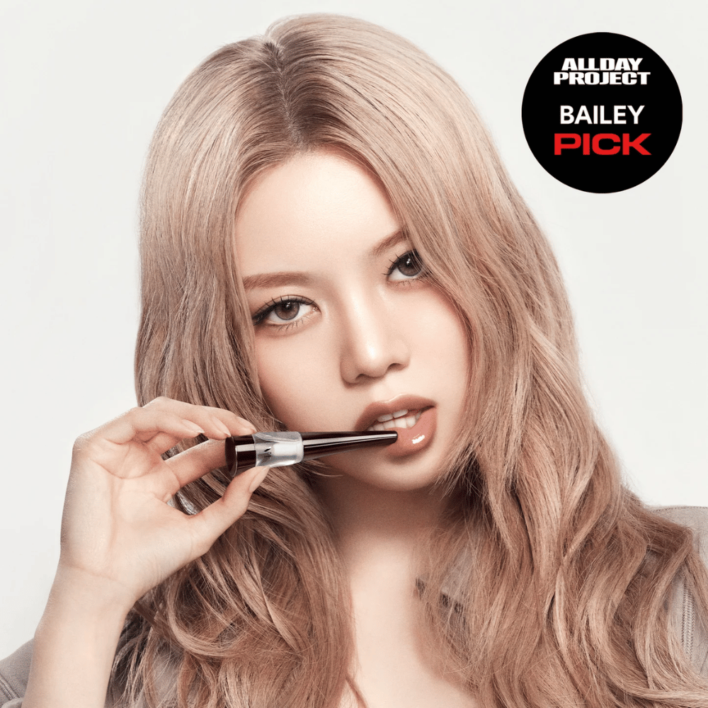 Modello applica VT Reedle Shot Lip Plumper Expert sulle labbra, finitura lucida e labbra più piene, contrassegnato come Bailey Pick da All Day Project.