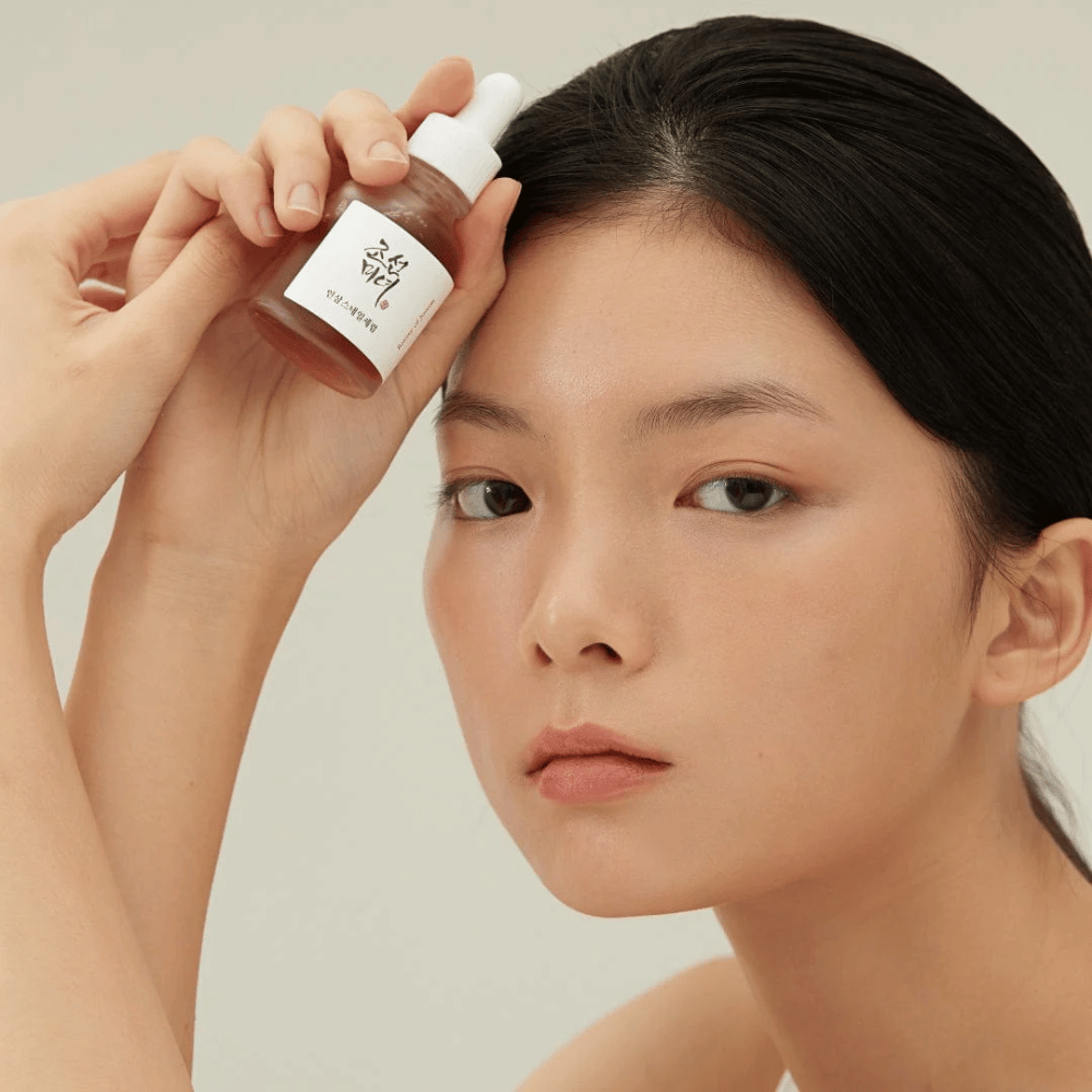 Modello tiene Beauty of Joseon Revive Serum sulla guancia – siero nutriente con ginseng e bava di lumaca.