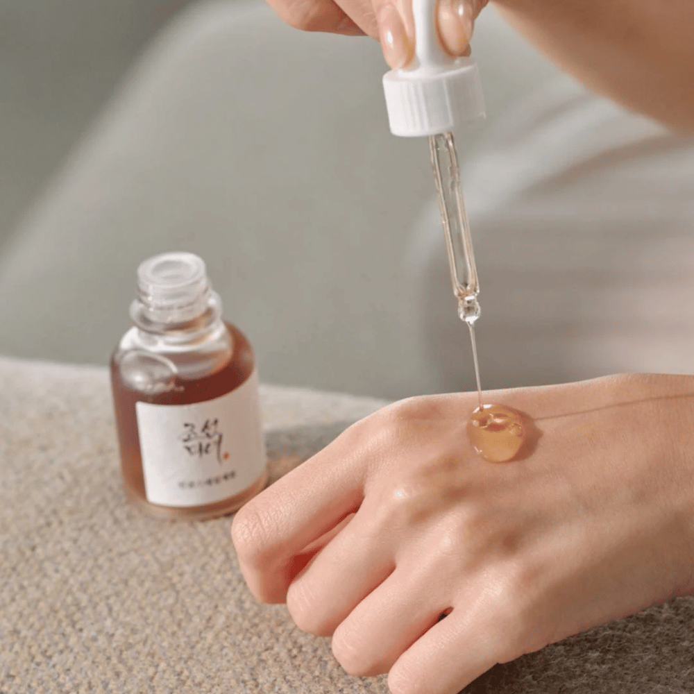 La pipetta fa cadere Beauty of Joseon Revive Serum Ginseng + Snail Mucin sulla pelle – siero coreano per elasticità e idratazione.