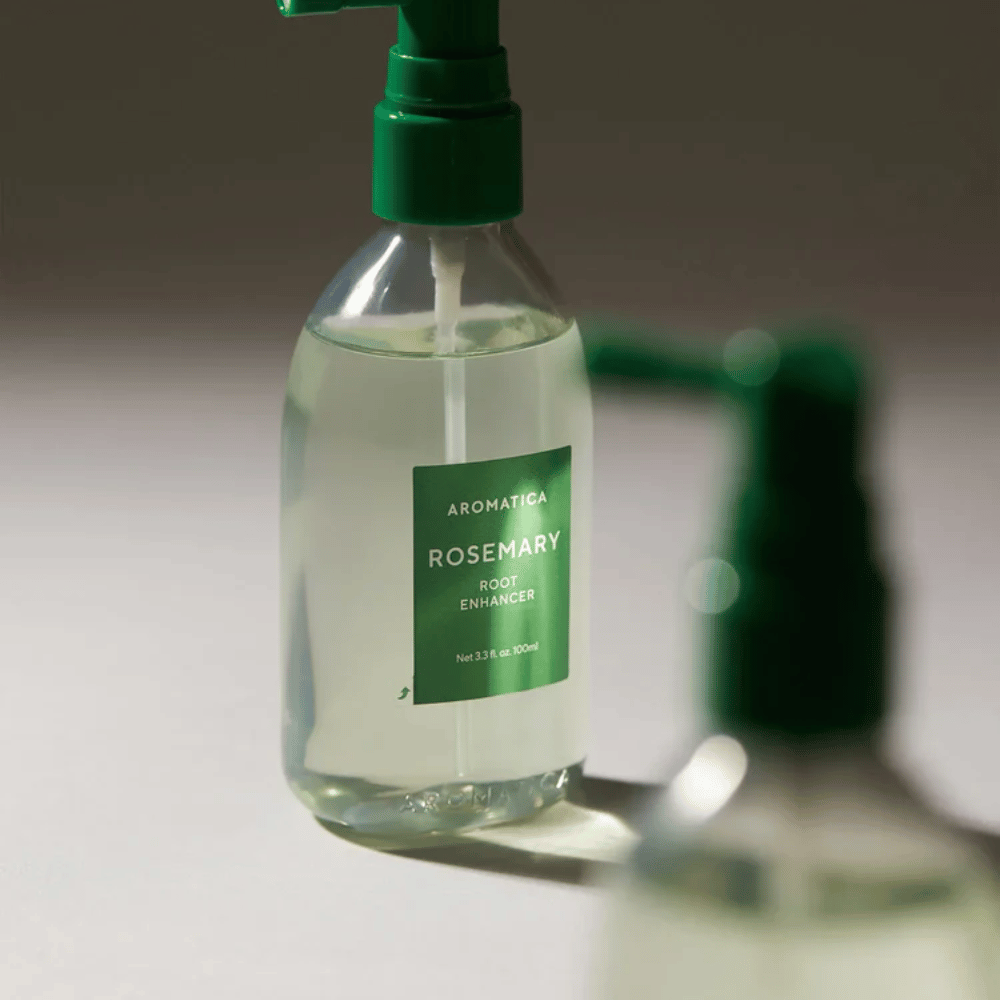 Primo piano di AROMATICA Rosemary Root Enhancer con beccuccio applicatore verde. L’immagine si concentra sul design del flacone e sull’applicazione precisa direttamente sul cuoio capelluto.