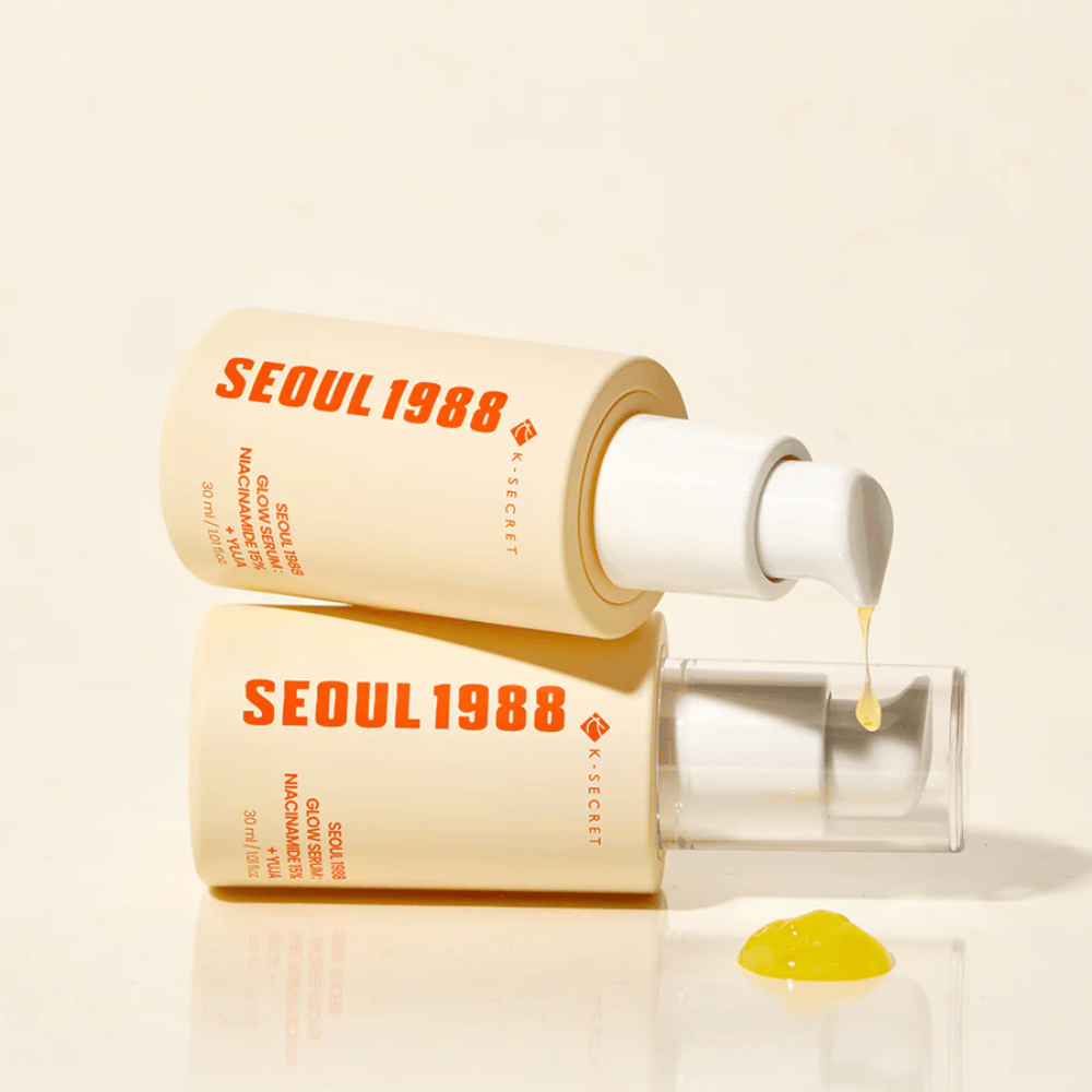 Due bottiglie di Seoul 1988 Glow Serum distese e in piedi, con siero giallo che gocciola dalla pompa.