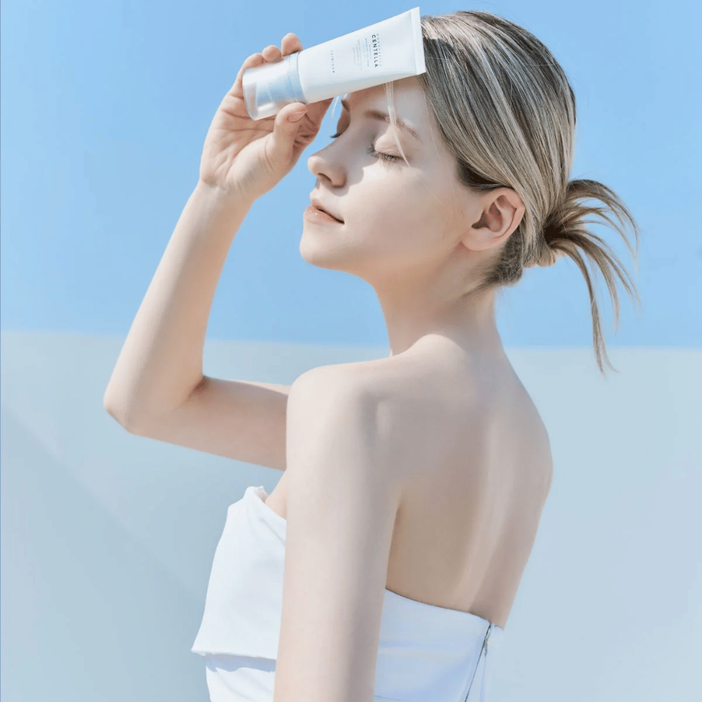 Una donna applica SKIN1004 Madagascar Centella Hyalu-Cica Water-Fit Sun Serum 50ml per proteggere il viso dai raggi UV.