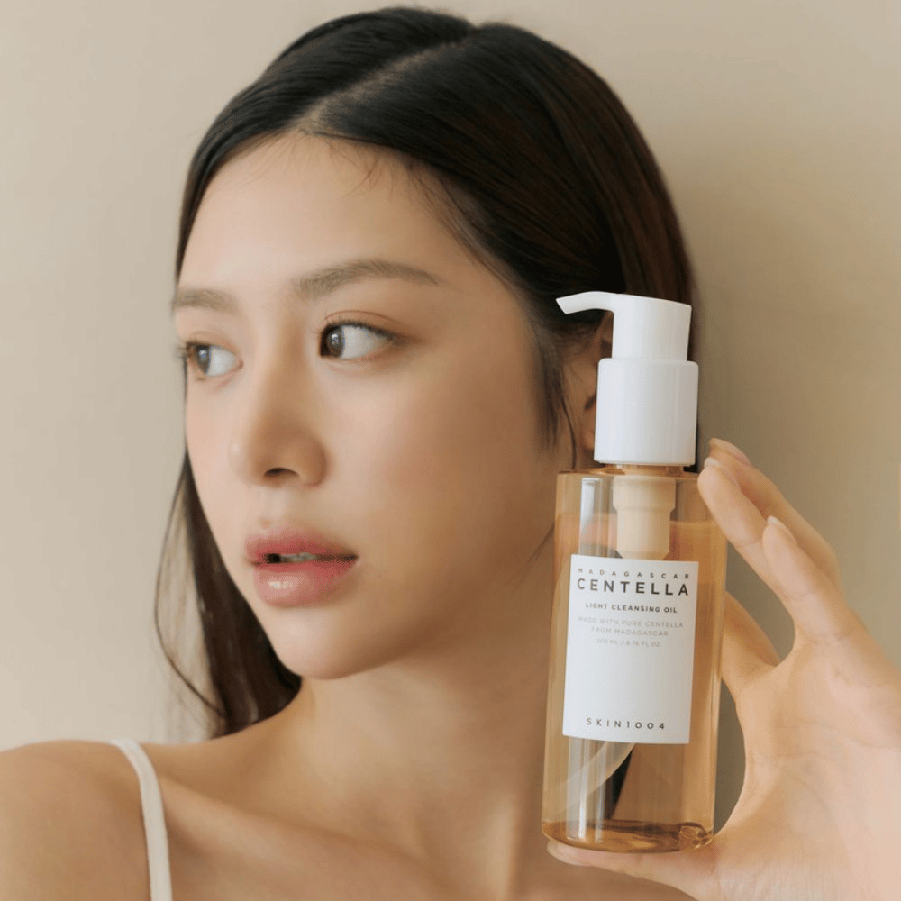 Una donna che tiene in mano una bottiglia SKIN1004 Madagascar Centella Light Cleansing Oil 200 ml detergente viso.