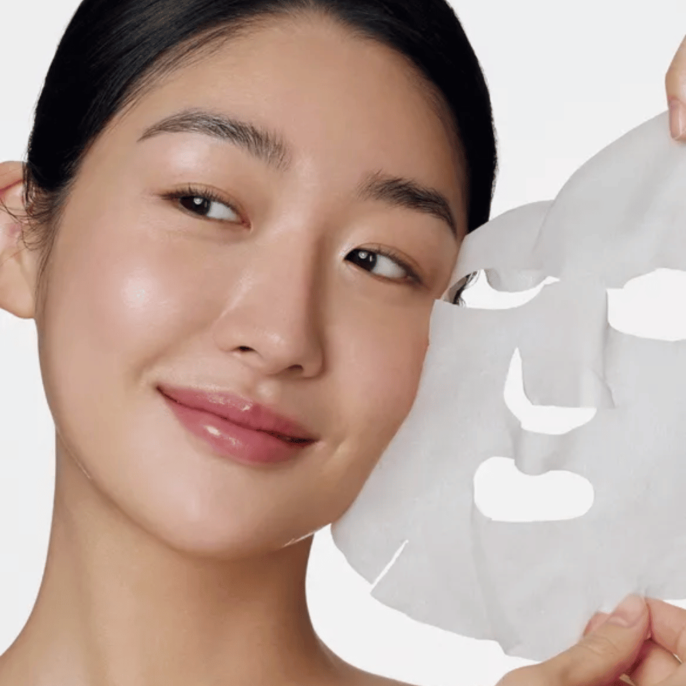 L'immagine mostra una persona che usa un maschera viso, specificamente un "Retinol Intense Daily Mask" da Some By Mi. La maschera è progettata per l'uso quotidiano e contiene retinolo per migliorare la texture della pelle, ridurre le linee sottili e dare un tono della pelle più uniforme.