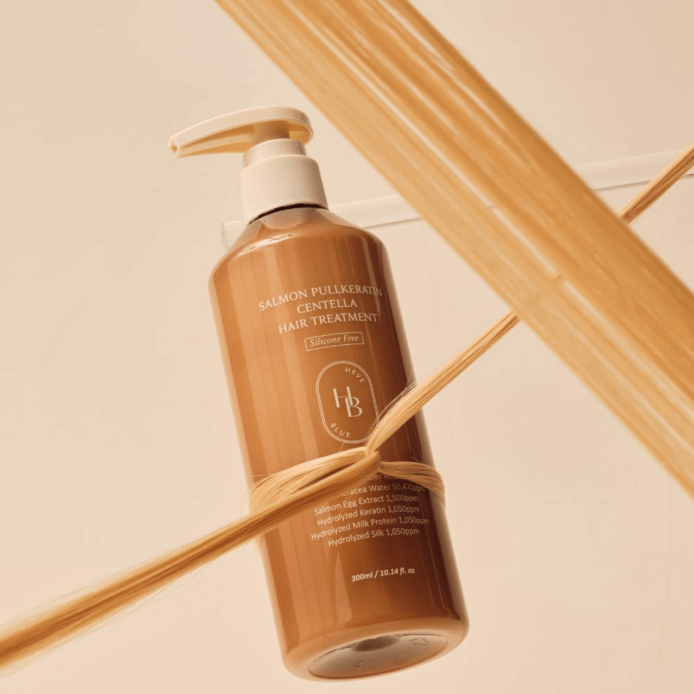 Heveblue Salmon Pullkeratin Centella Hair Treatment in flacone marrone circondato da ciocche di capelli. L’immagine mette in risalto le proprietà nutrienti del trattamento per capelli con focus su lucentezza, forza e capelli setosi.