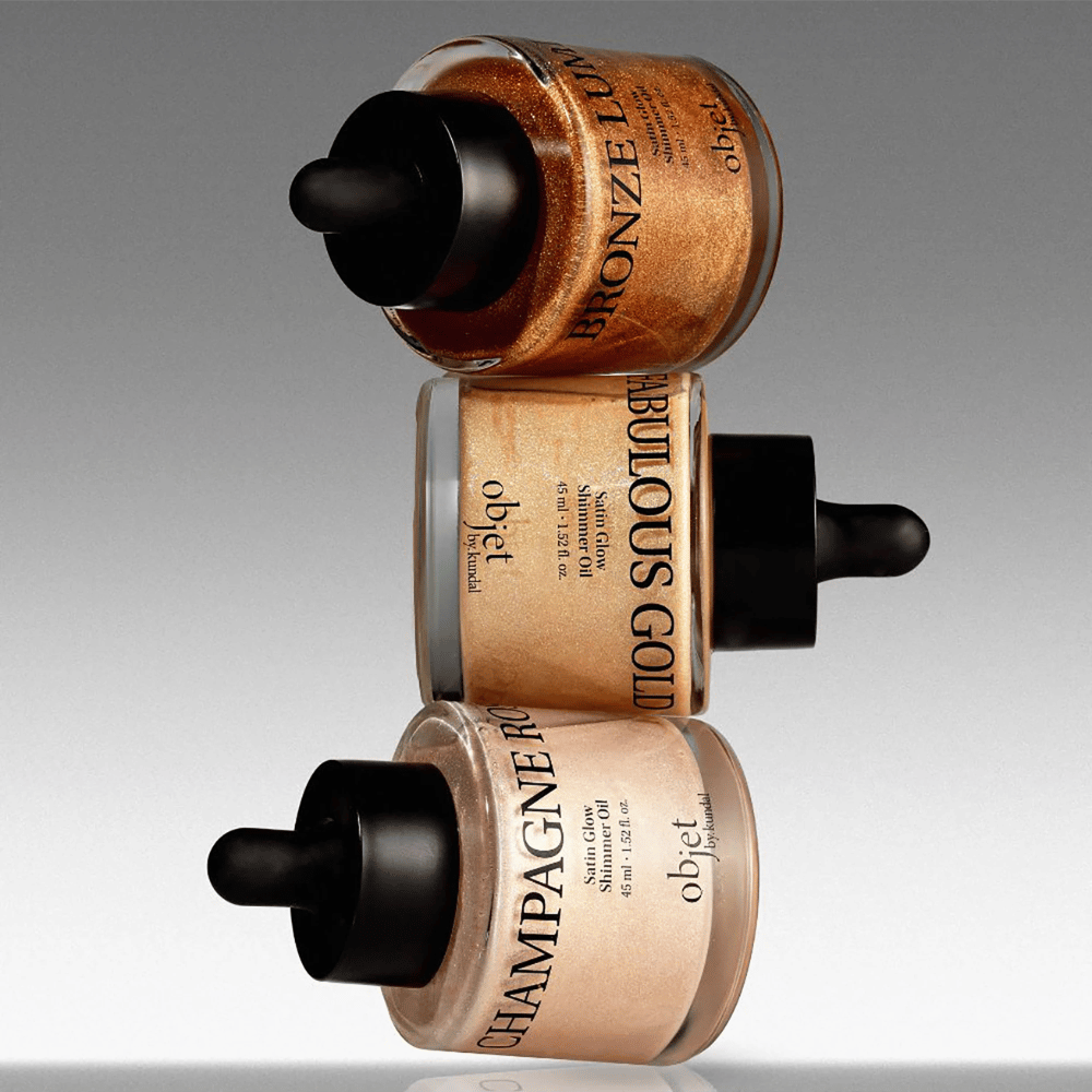 Objet by KUNDAL Satin Glow Shimmer Oil in Bronze Lumière, Fabulous Gold e Champagne Rose – oli corpo scintillanti con finitura illuminante.