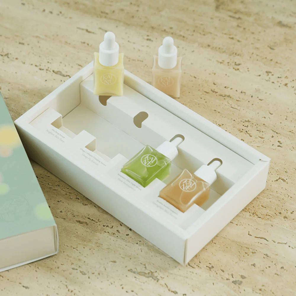 Quattro bottiglie di siero colorate di KAINE Serum Discovery Kit con tappo contagocce, progettate per soddisfare diverse esigenze della pelle in un packaging minimalista ed elegante.