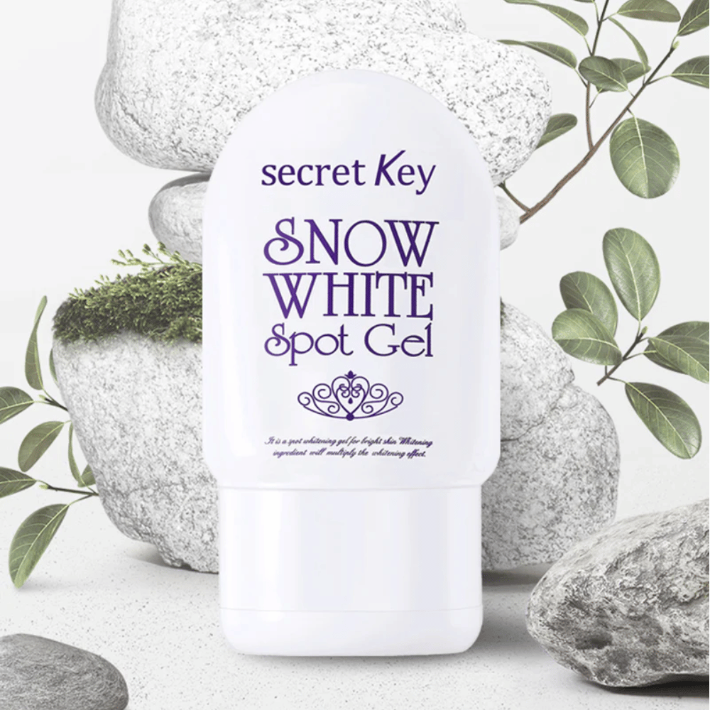 Secret Key Snow White Spot Gel fotografato contro pietre e foglie verdi.