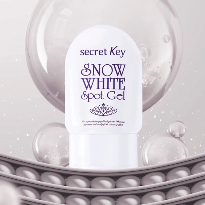 Secret Key Snow White Spot Gel i vit förpackning mot bakgrund med bubblor och pärlliknande detaljer.