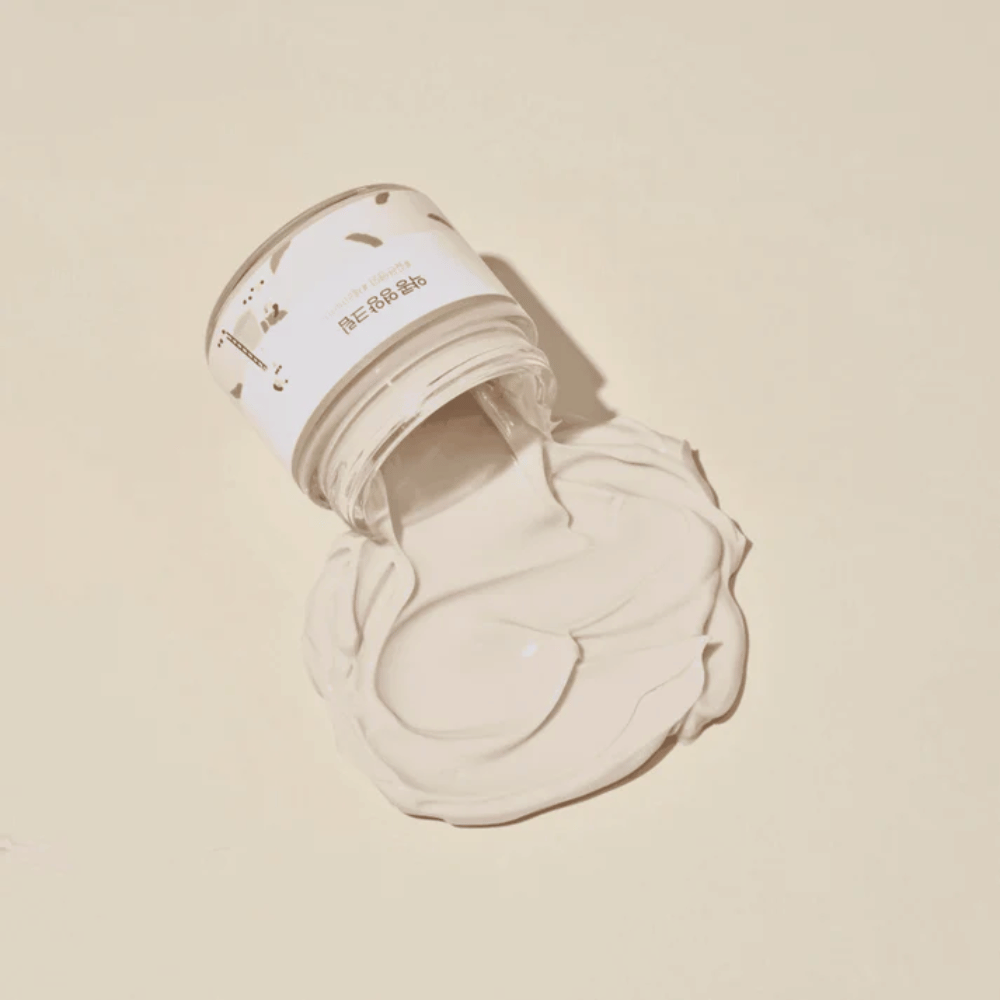 Mixsoon Soybean Nourishing Cream versata dal barattolo su uno sfondo beige. La consistenza ricca della crema mostra le sue intense proprietà idratanti.