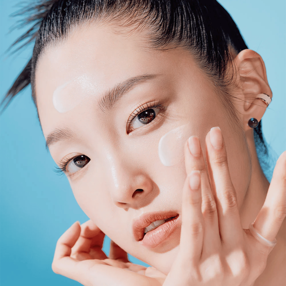 Una donna posa con le mani sul viso in una TOCOBO Bio Watery Sun Cream SPF50+ PA++++ campagna di cura della pelle naturale da 50ml.