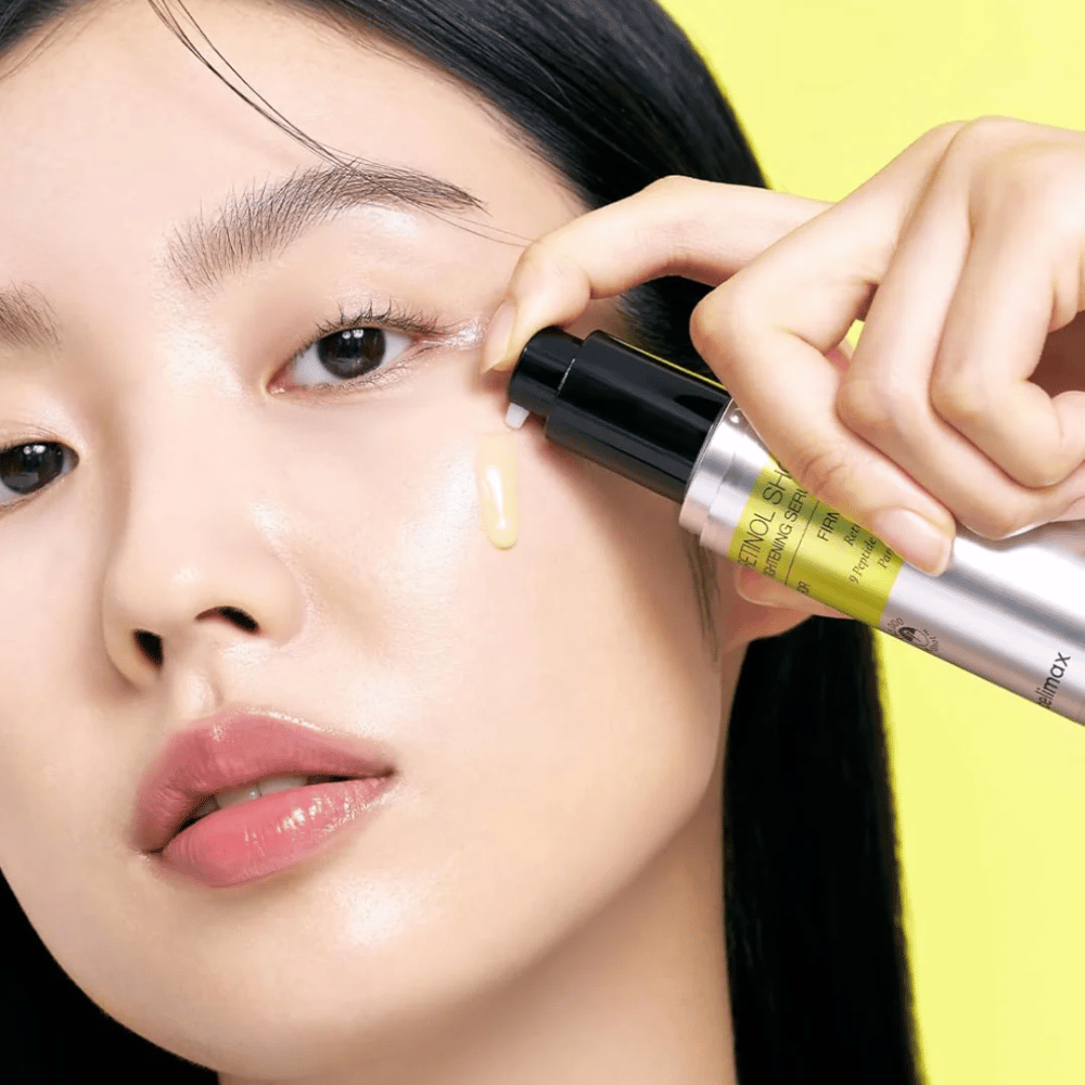 Modello applica The Vita-A Retinol Shot Tightening Serum da Tiam vicino alla zona degli occhi, con attenzione alla luminosità della pelle e alla consistenza gialla del siero.