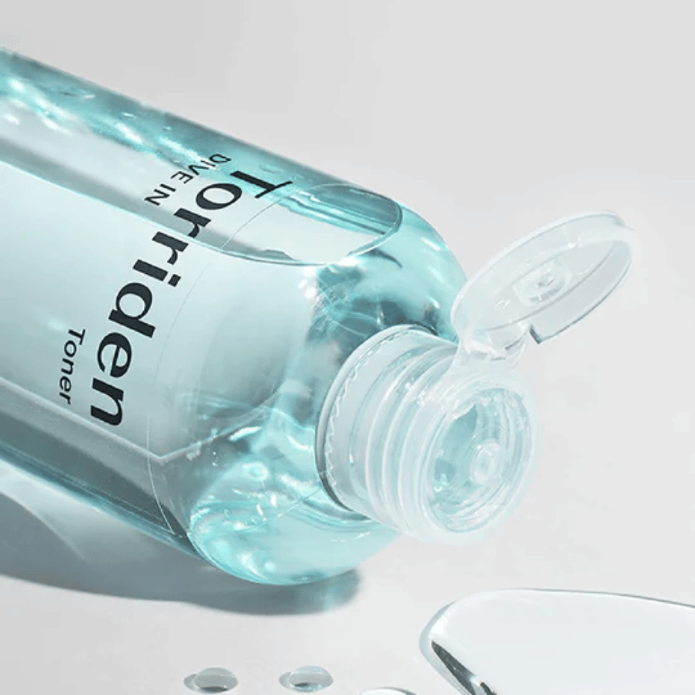 Una bottiglia DIVE-IN Low Molecule Hyaluronic Acid Toner 300ml accanto a un bicchiere d'acqua, promuove Torriden e idratazione.