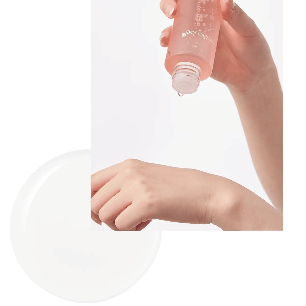 Mano che applica Medicube Triple Collagen Tonico viso 4.0 dalla bottiglia rosa sulla pelle, mostrando la consistenza idratante.