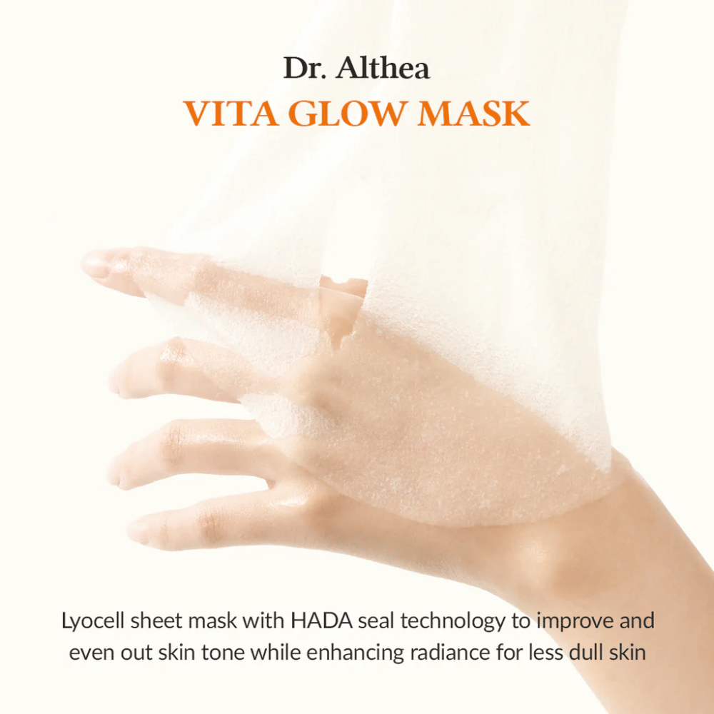 Mano tiene un lyocell sheet mask da Dr. Althea Vita Glow Mask. La maschera migliora la luminosità e l'uniformità della pelle con la tecnologia HADA Seal.