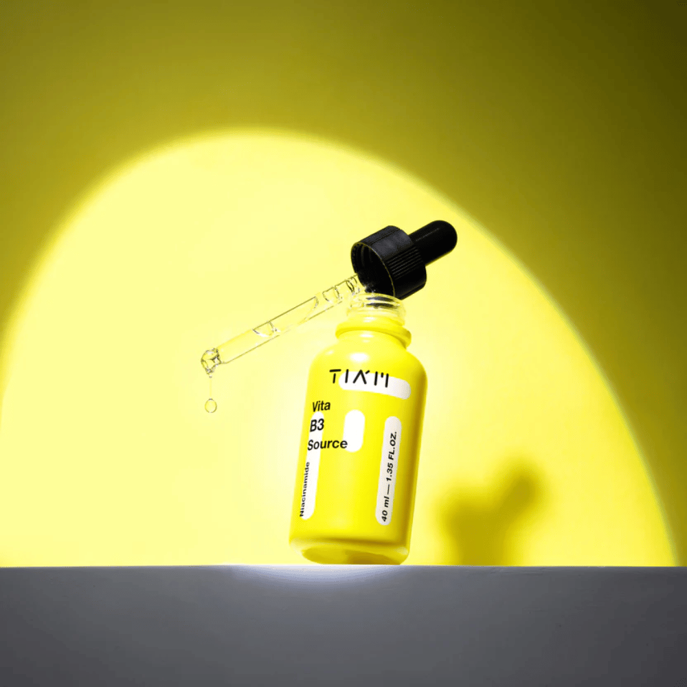 TIA'M Vita B3 Source – siero alla niacinamide in flacone giallo con pipetta, progettato per illuminare la pelle e dare un tono più chiaro.