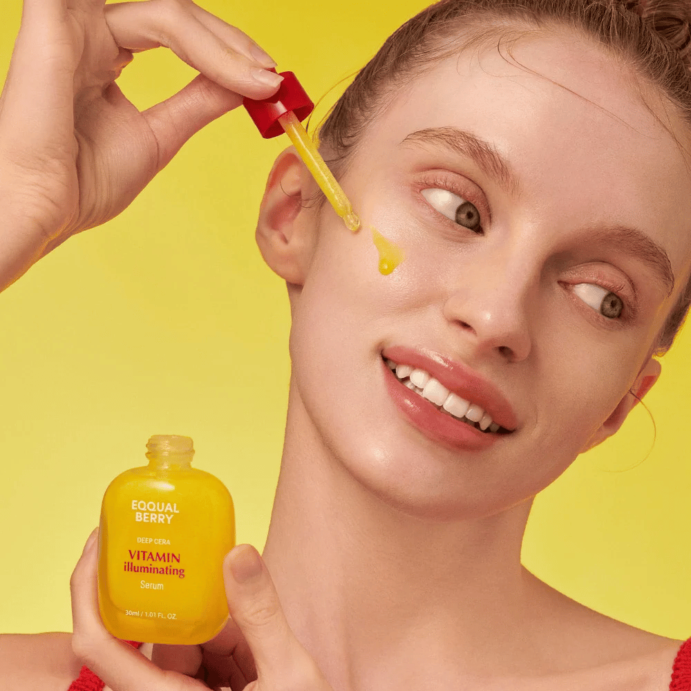 Donna sorridente applica Equal Berry Vitamin Illuminating Serum con una pipetta. Pelle fresca e radiosa su uno sfondo giallo vivace che si abbina al colore del siero.
