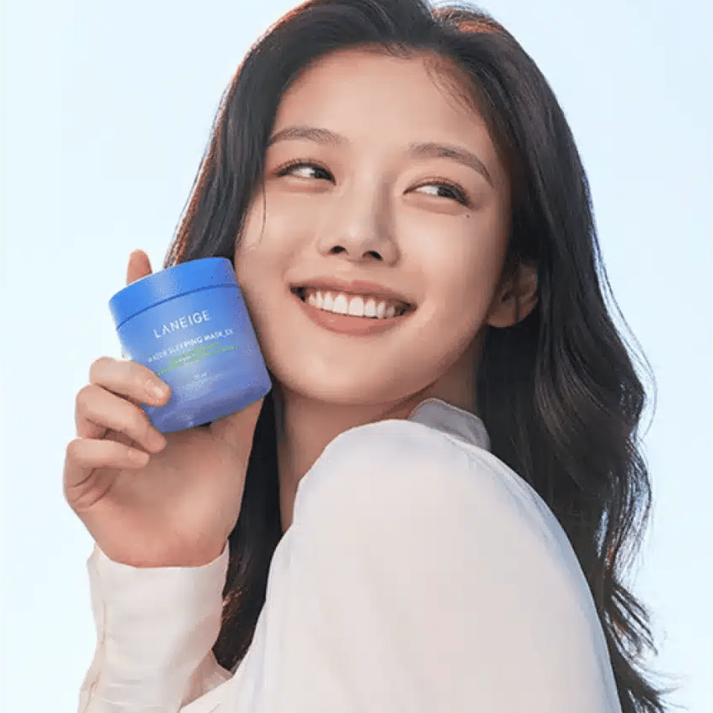 Donna sorridente tiene un barattolo blu di LANEIGE Water Sleeping Mask davanti a uno sfondo azzurro.