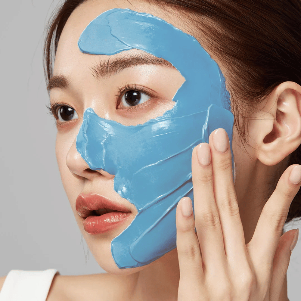 Modello con maschera viso blu da Medicube, copre la zona T per la cura dei pori.