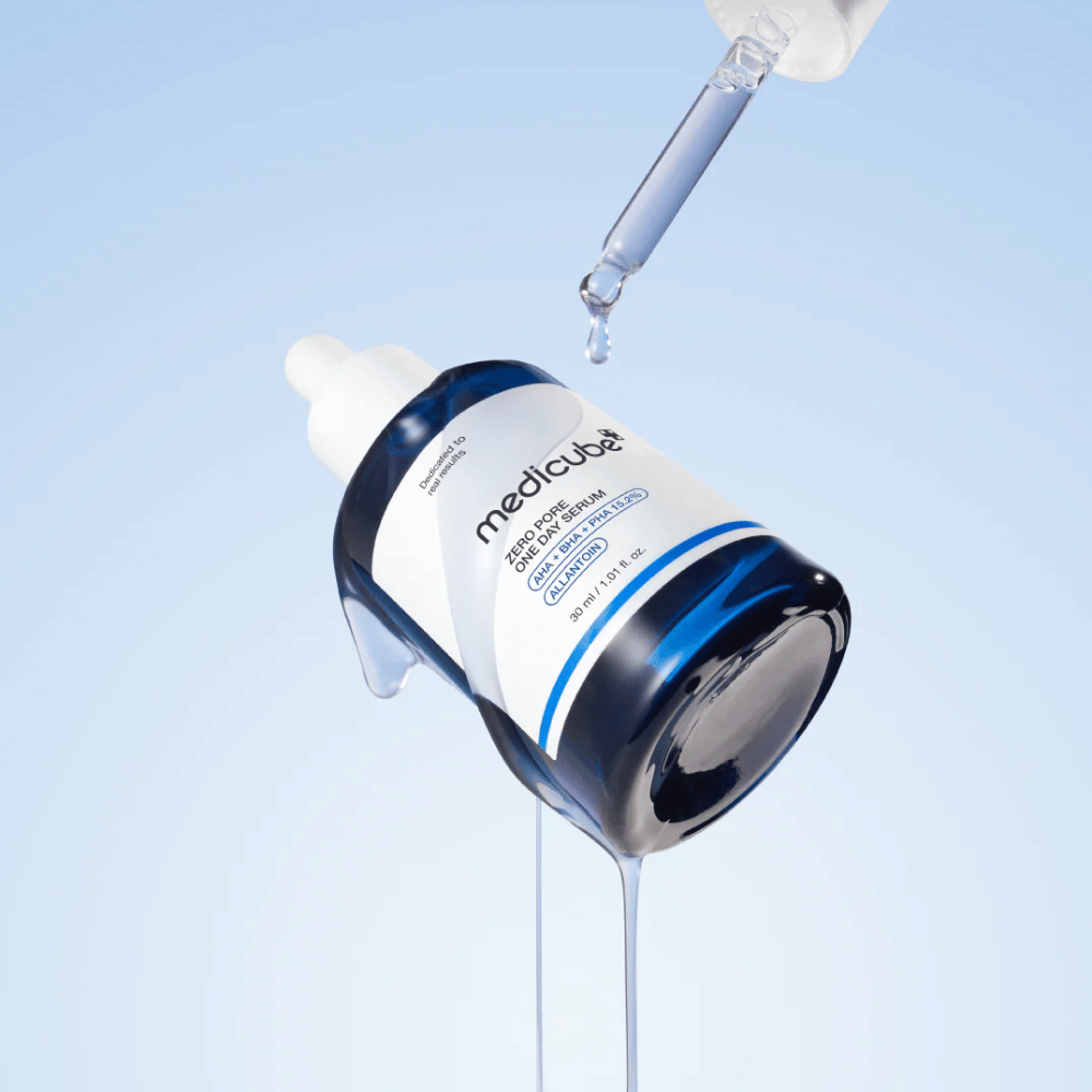 Bottiglia di Medicube Zero Pore One Day Serum con pipetta e gocce di siero che scorrono su uno sfondo azzurro chiaro.