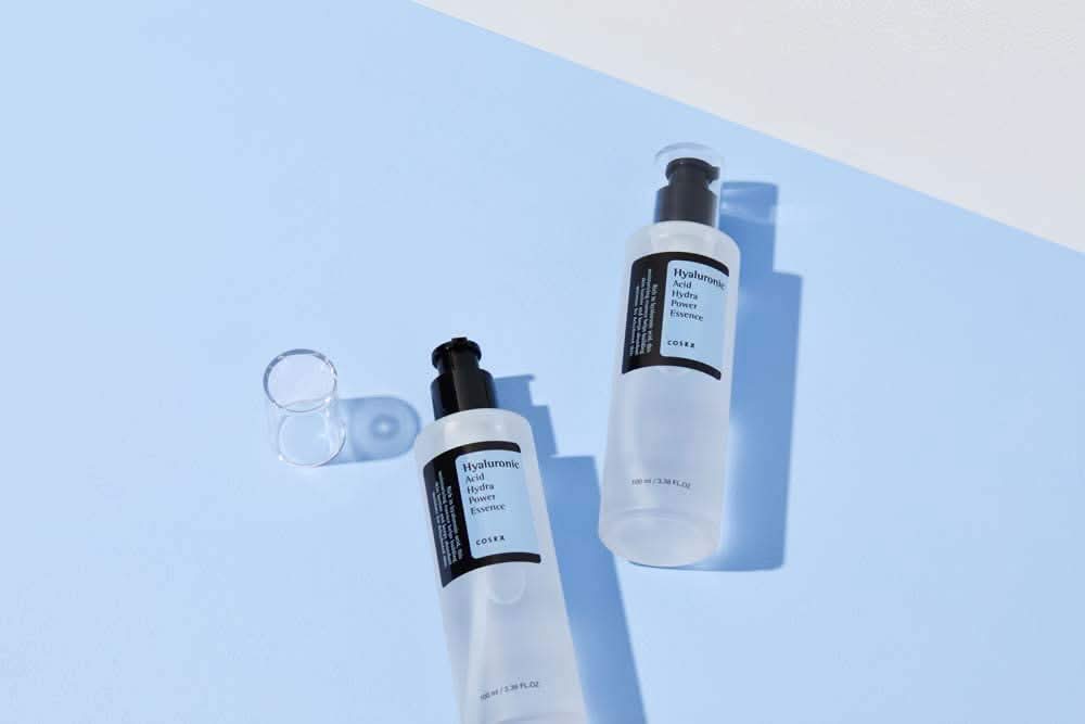 Il COSRX:s Hyaluronic Acid Hydra Power Essence 100ml fornisce benefici idratanti sulla superficie blu.