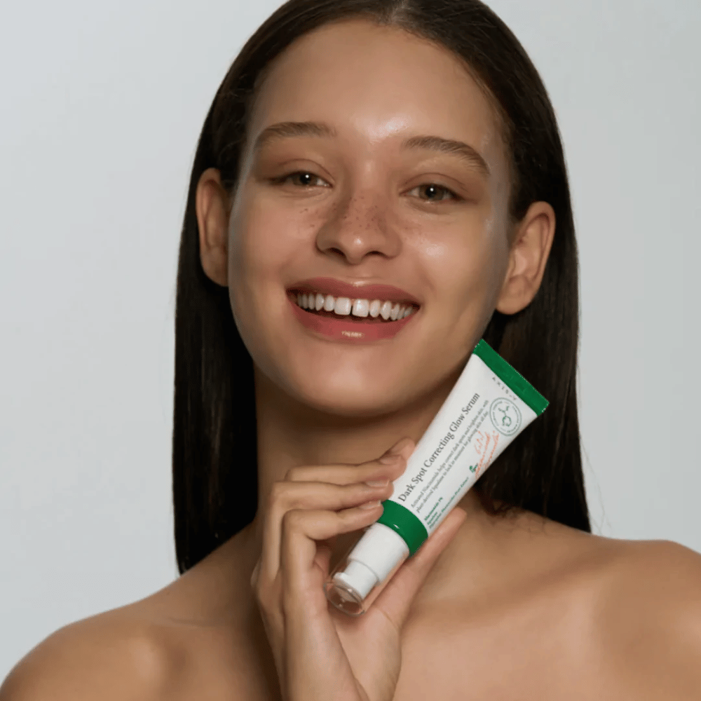 Una giovane donna tiene in mano un tubo di AXIS - Y Dark Spot Correcting Glow Serum 50ml.