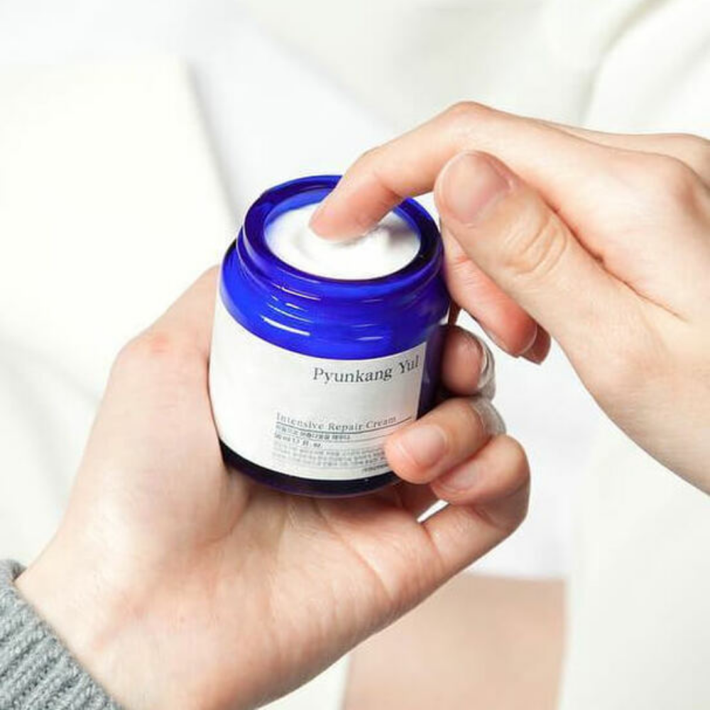 Una persona tiene in mano un barattolo Pyunkang Yul Intensive Repair Cream 50ml.