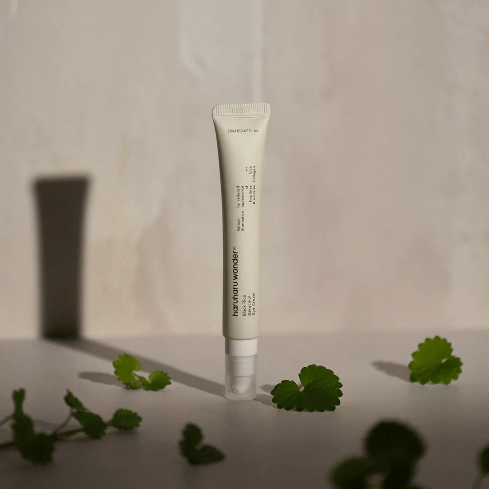 Un tubetto Haruharu Wonder Black Rice Bakuchiol Eye Cream 20ml circondato da foglie verdi, focalizzato sulla visibilità delle rughe e delle linee sottili.