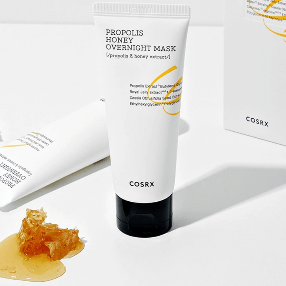 Una scatola Full Fit Propolis Honey Overnight Mask 60ml da COSRX con una bottiglia di miele accanto, con estratto di propoli.