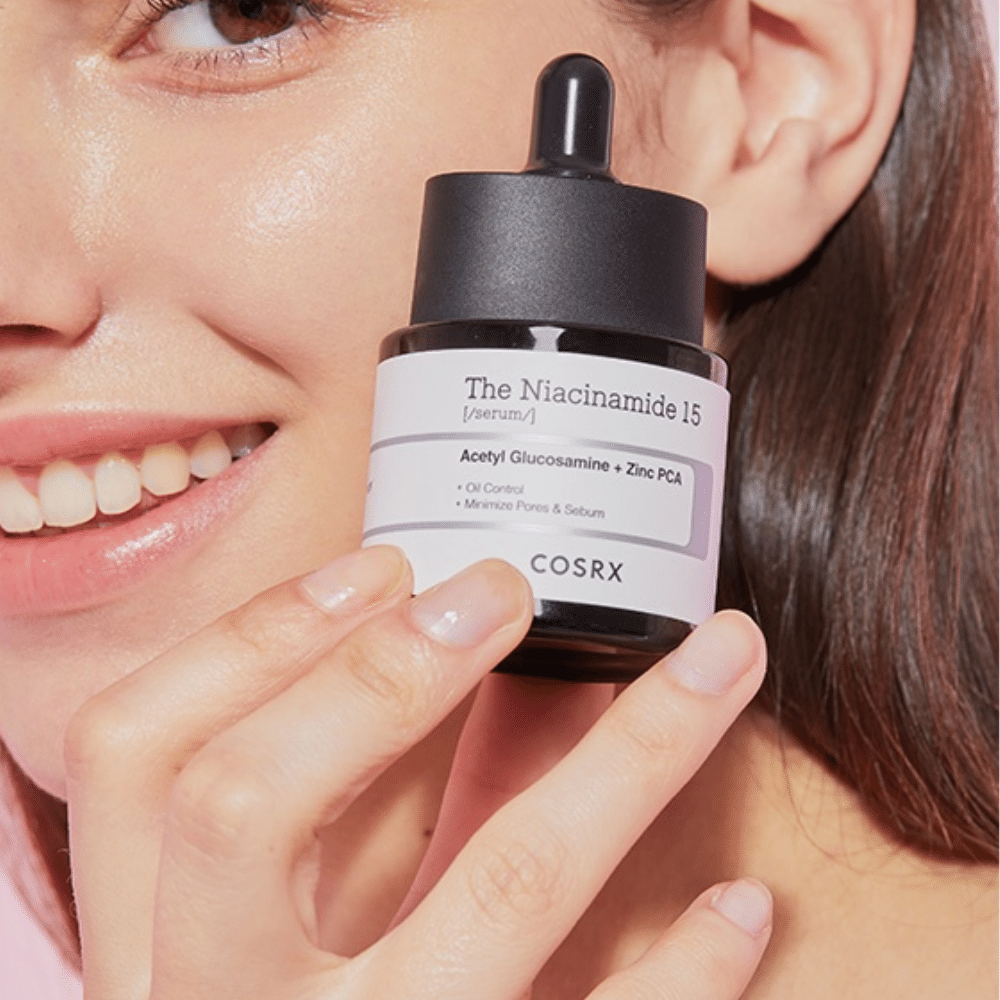 Una donna tiene in mano una bottiglia di COSRX Niacinamide 15 Serum 20ml per niacinamide e la produzione di sebo.
