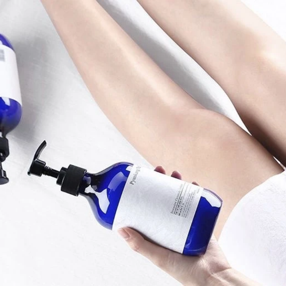 Una donna che tiene una bottiglia Pyunkang Yul Intensive Ceramide Lotion 500ml accanto alle sue gambe.