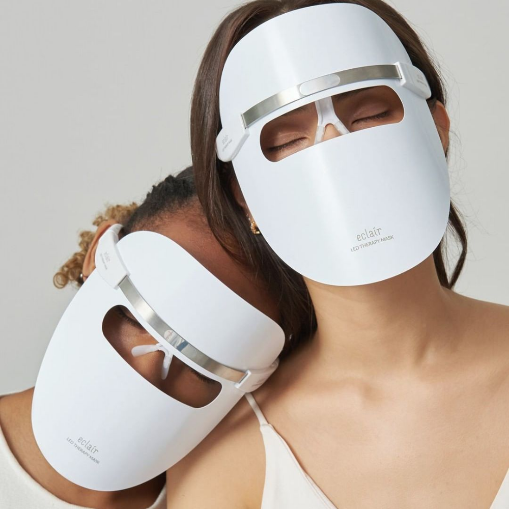 Due donne che indossano maschere bianche dimostrano ECLAIR LED Therapy Mask per miglioramenti del tono della pelle.