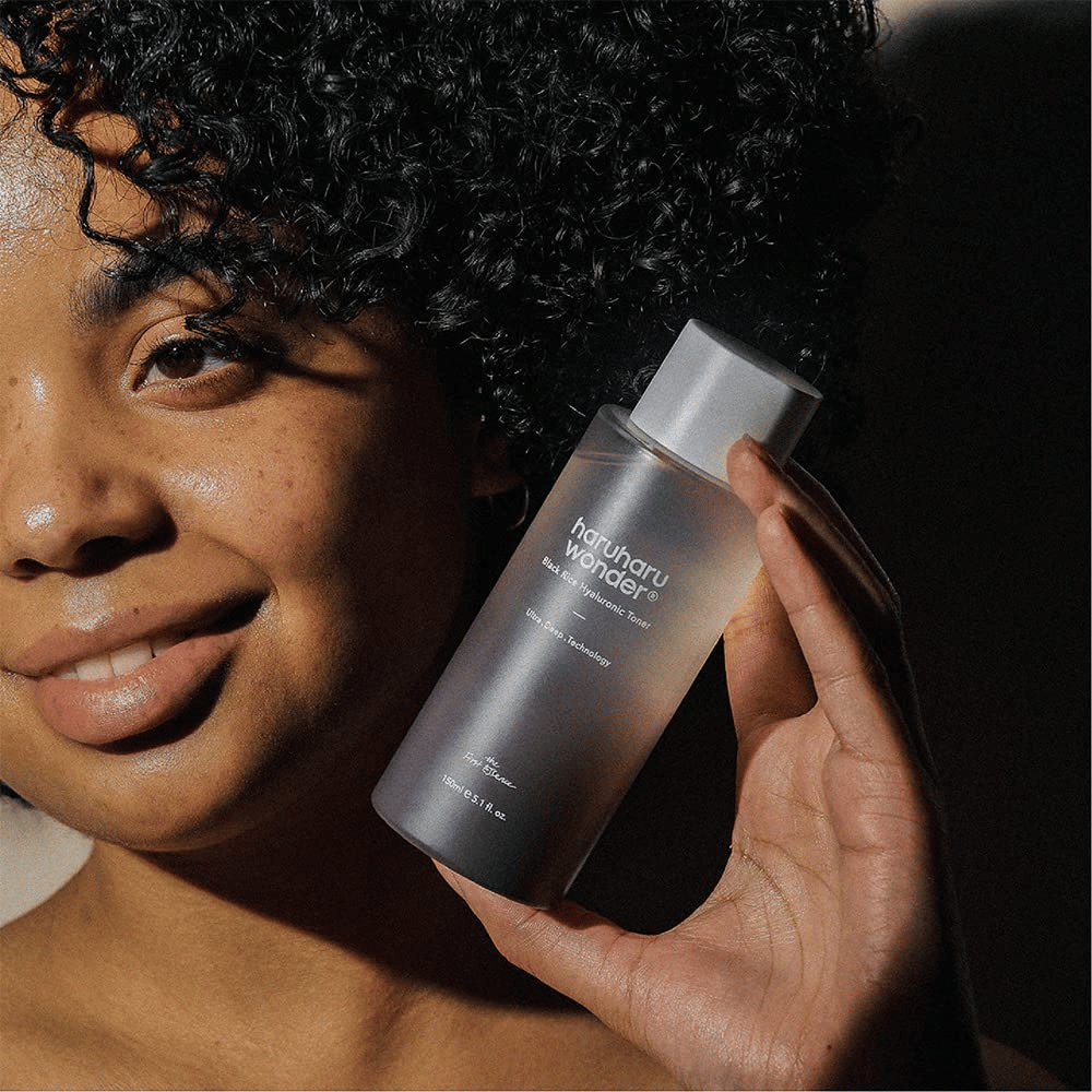 Una donna che tiene in mano una bottiglia di Haruharu Wonder Black Rice Hyaluronic Toner Original 150ml.