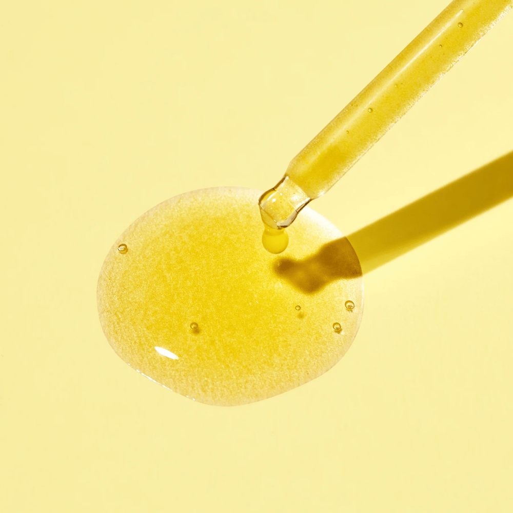 Una goccia di liquido su uno sfondo giallo, con MISSHAs Vita C Plus Spot Correcting & Firming Ampoule.
